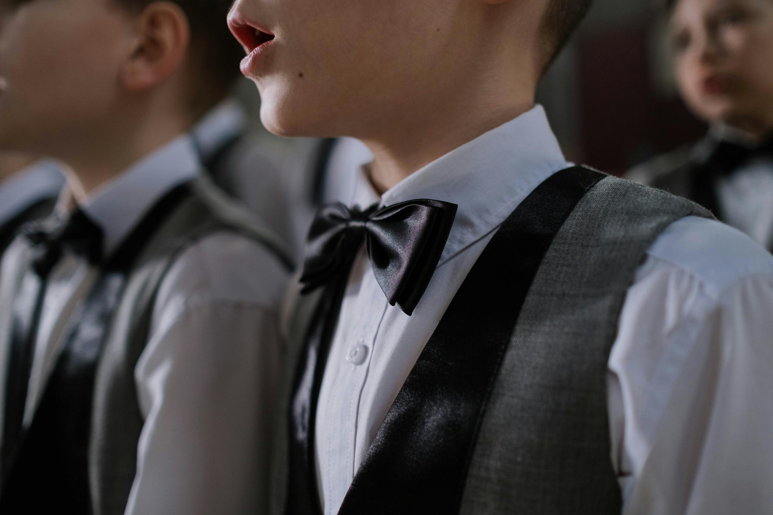 Young boys dressed in formal wear singing in a choir, focused on elegance and unity.